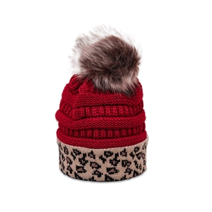 Detail of red knit beanie featuring a brown faux fur pompom and leopard print cuff