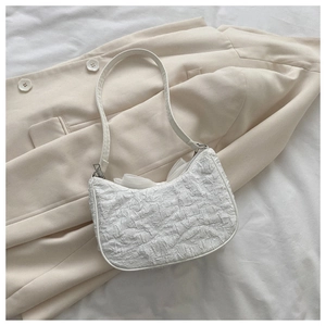 Detail of white bubble pleated texture shoulder bag on a beige blazer background