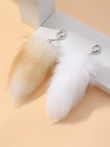 Detail view of fluffy faux fur fox tail keychains in white and light brown with metal clips