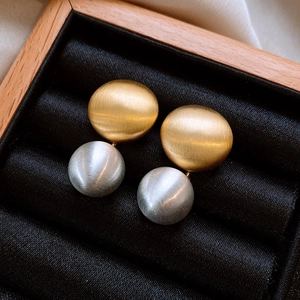Gros plan de boucles d'oreilles dorées et argentées à texture métallique brossée
