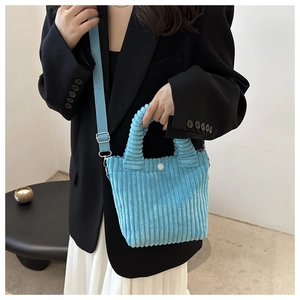 Close-up of sky blue corduroy bucket bag featuring textured vertical stripes and white snap button