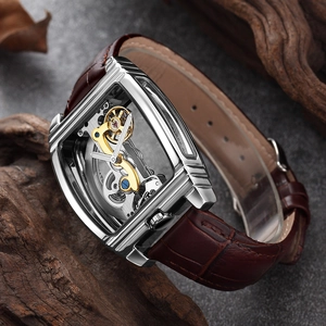 Detail of tonneau-shaped skeleton mechanical watch with golden gears and leather strap
