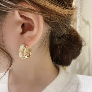 Elegant gold double-layered C-shaped hoop earrings with chain detail worn by a model