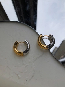 Close-up of gold and silver two-tone hoop earrings with high-polished metal finish