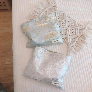 Detail of rose floral jacquard makeup bags in light blue and silver with woven label
