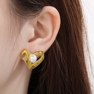 Macro detail of French vintage heart earring featuring a pearl and gold brushed texture