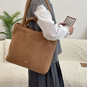 Brown teddy fleece tote bag with brand patch shown in a cozy lifestyle scene