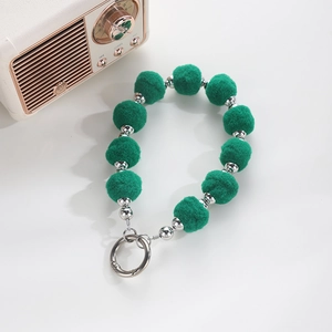Detailopname van groene pluche ballen en zilveren kralen met een ronde veersluiting