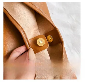 Detailed close-up of the golden magnetic buckle on this premium brown leather tote bag