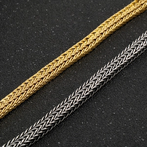 Close-up of gold and silver stainless steel dragon bone bracelets with Spiga weave