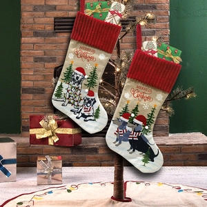 Knitted Christmas stockings with dog patterns hanging on a fireplace mantel with gifts