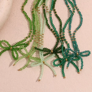 Detail view of green faceted crystal beads and bow design necklace with gold accents