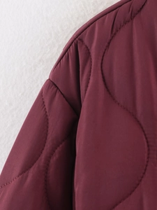 Detail shot of wine red quilted cotton jacket showing delicate wave stitching texture