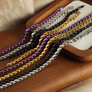 Leaf charm chain necklaces in gold, silver and black finishes on a rustic wood tray