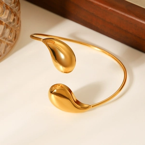 Close-up of golden teardrop bangle showing polished stainless steel and mirror-like finish