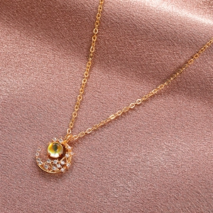 Macro detail of a golden moon pendant with shimmering stones on a soft silk background