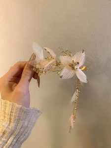 Detail of pink fabric petals, pearls, and rhinestones on a gold tassel hair clip