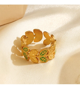 Macro shot of gold-plated leaf ring with green enamel detailing on silk background