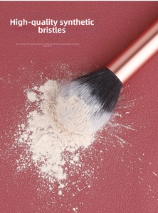 Detail of high-quality fiber brush head picking up loose powder on a pink background