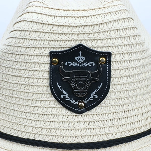 Macro shot of retro bull head metal badge and leather patch on straw cowboy hat