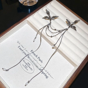 Detailed view of twin phoenix pins with pearl tassels on vintage art box
