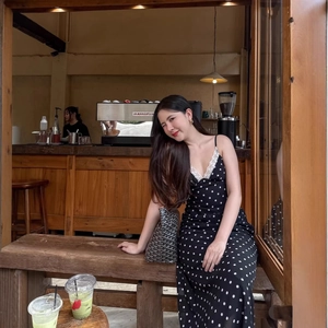 Robe longue à pois avec bordure en dentelle portée par un mannequin dans un café chaleureux