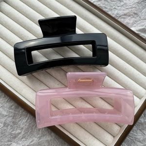 Detail view of black and pink jelly hair claws on a beige velvet jewelry display tray
