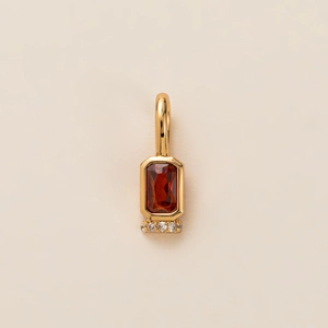 Detailed view of a gold pendant featuring a rectangular red gemstone and diamond accents