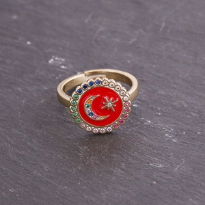 Gold open ring with red enamel celestial moon and star patterns on stone background