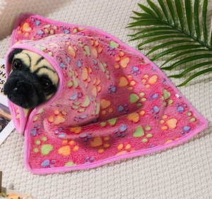 Close-up of soft pink flannel pet blanket with colorful paw prints on a pug plush toy