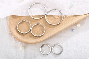 Three pairs of silver stainless steel hoop earrings with crystal pavé on a tray