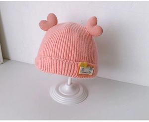 Detailed close-up of pink knitted baby hat featuring two heart decorations and Good Life label