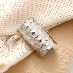 Polished silver wide ring with honeycomb textured metal surface on a natural wood background