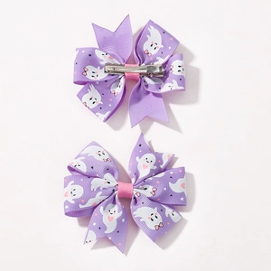 Close-up of purple Halloween bow hair clips with ghost and star patterns and metal clip back