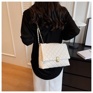 Detailed back view of a white quilted shoulder bag with golden chain strap on a model