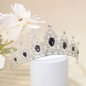 Detailed view of silver crown with purple teardrop gems and crystals on a pedestal