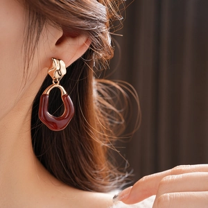 Close-up of elegant amber resin oval earrings with textured gold metal detail on model