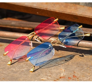 Close-up of rimless gradient sunglasses on industrial metal stand with gold temple details