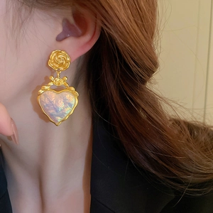 Gros plan sur les boucles d'oreilles vintage fleurs et cœurs au fini nacré iridescent