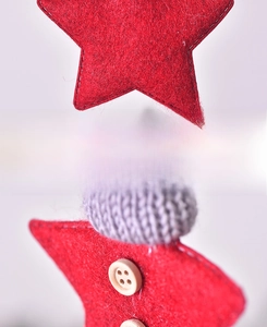 Detail of red felt star ornament with grey knitted cap and wooden button back view