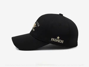 Detail of gold embroidery on black baseball cap featuring stars and fashion text