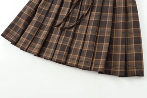 Detailed macro shot of brown plaid pleated mini skirt with refined texture and tie design