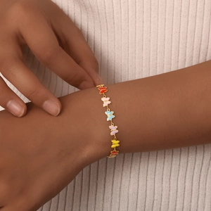 Close-up of golden slim chain bracelet with multi-color enamel butterfly charms on wrist