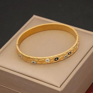 Golden Evil Eye bangle with hammer-textured finish on beige jewelry display box