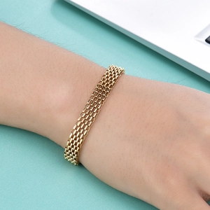 Minimalist 18K gold 8mm wide woven chain bracelet worn by a model in a stylish office setting