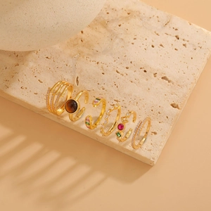 Close-up of a six-piece set of gold-plated geometric rings with tiger eye and zircon details