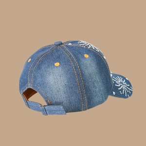 Vue détaillée de la casquette en jean montrant coutures orange et motif étoile en strass