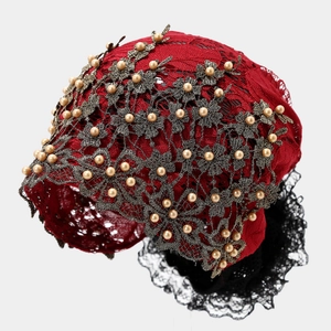 Détail du turban ethnique en dentelle rouge avec broderies florales et perles blanches