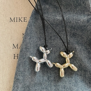 Y2K style gold and silver balloon dog pendants on black necklaces over denim background