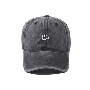Close-up of vintage washed dark gray denim baseball cap with white smiley face embroidery